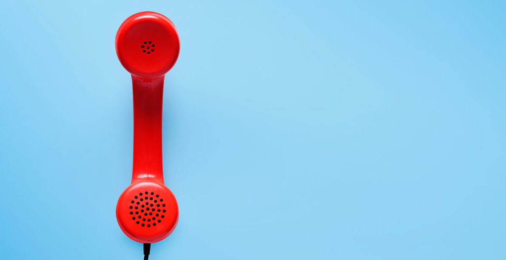 Motiv roter Telefonhörer liegt auf Himmelblauem Hintergrund